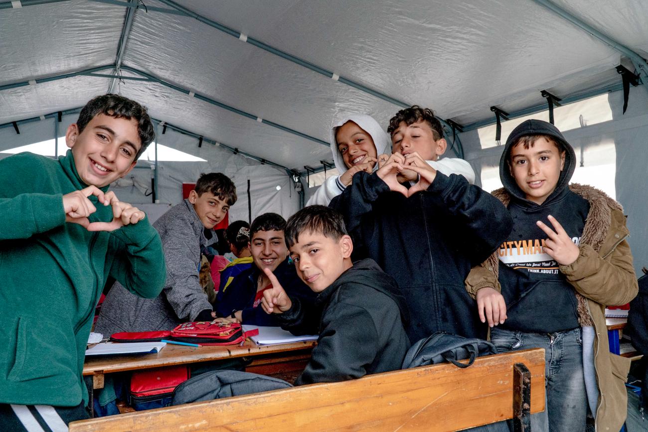 Children inside education tent making heart shapes with their fingers