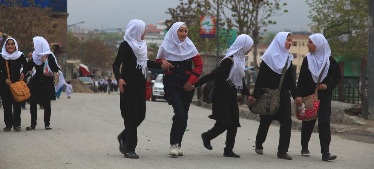 Beyaz başörtülü genç kızlar yolda yürüyor.