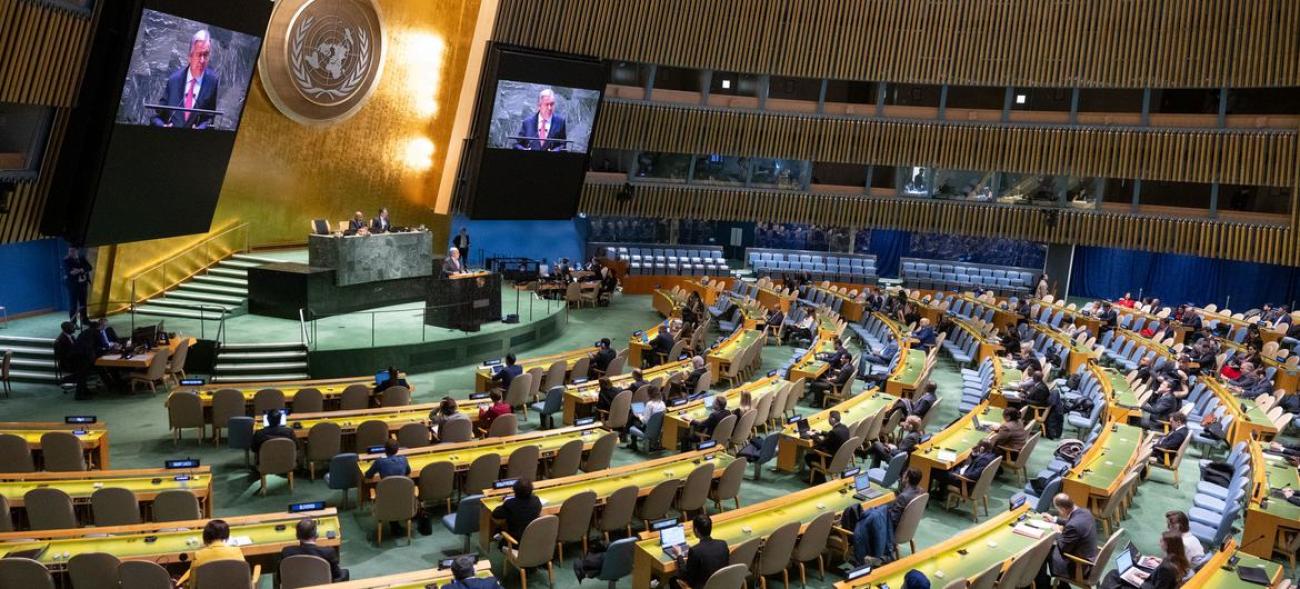 BM Genel Kurulu salonu. Genel Sekreter Guterres konuşuyor. Büyük ekranlara görüntüsü yansımış
