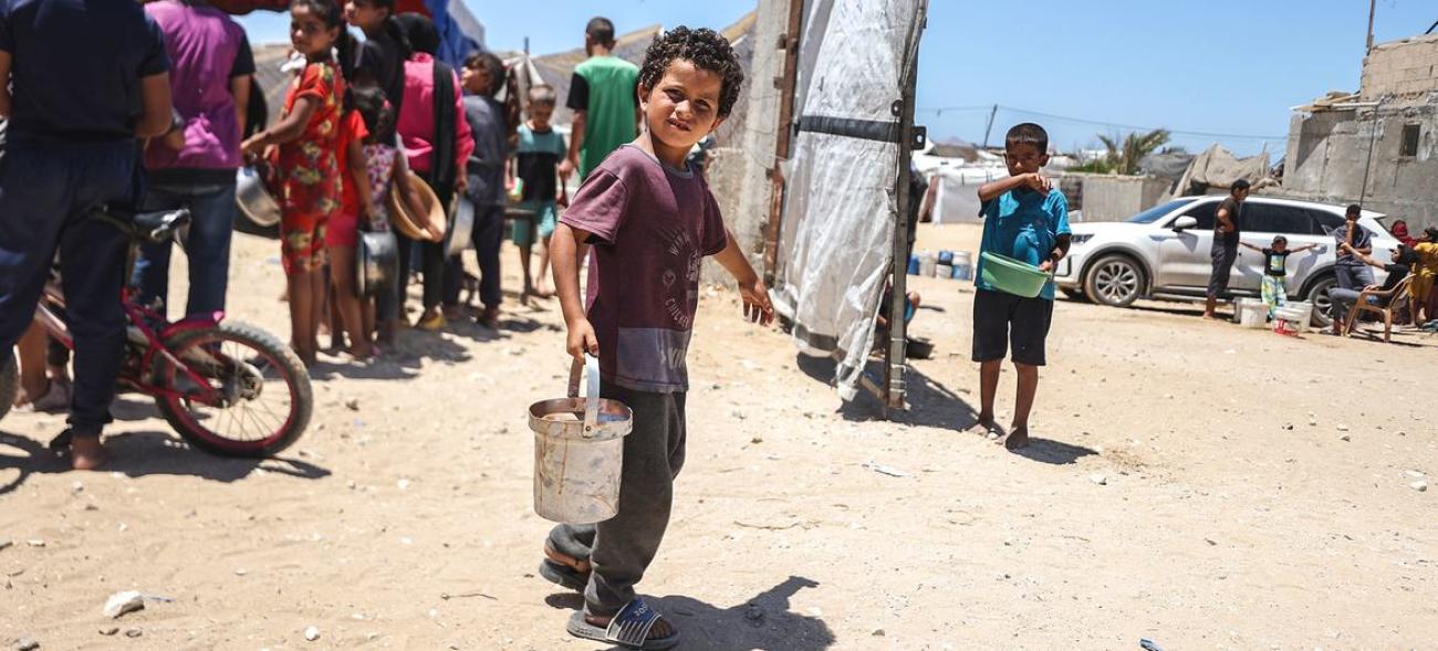 A child carrying a bucket filled with food