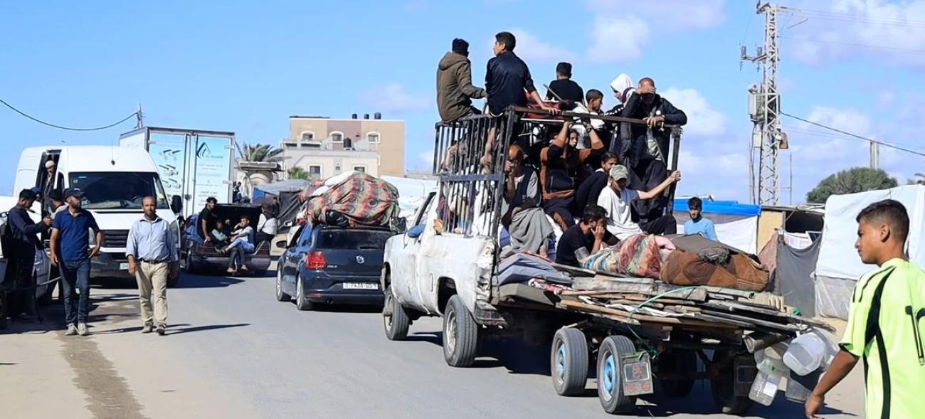 A busy road with people walking or on packed various vehicles with their packages, materials. They are on the move. 