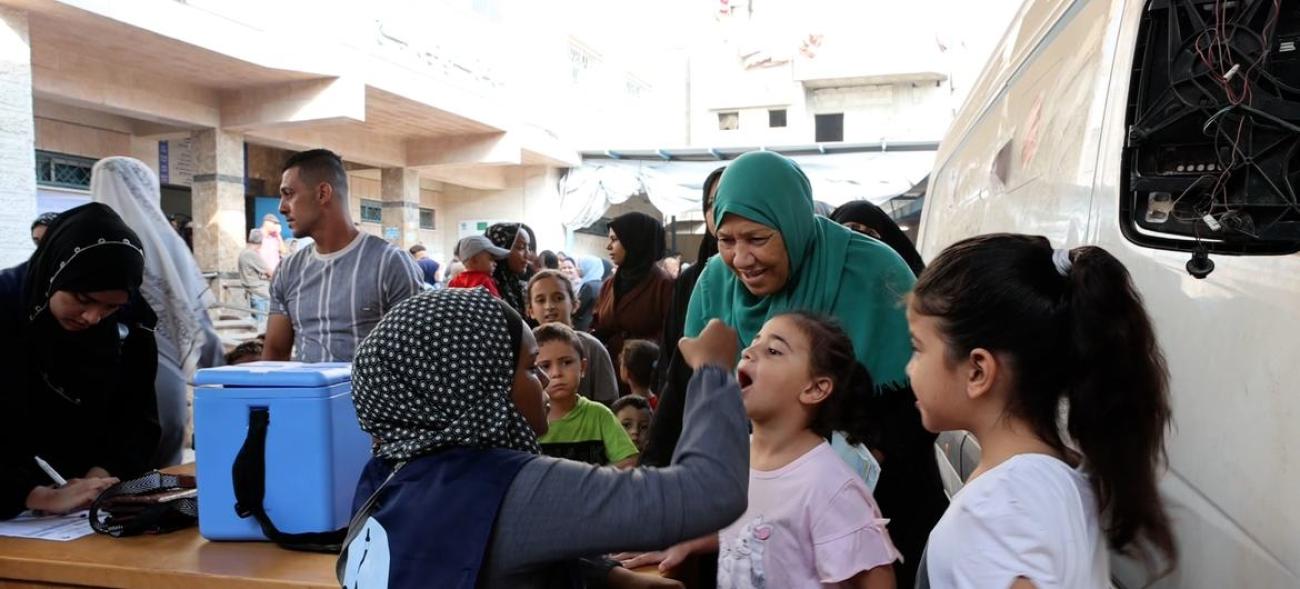 A child opened her mouth for polio vaccine as several others look.