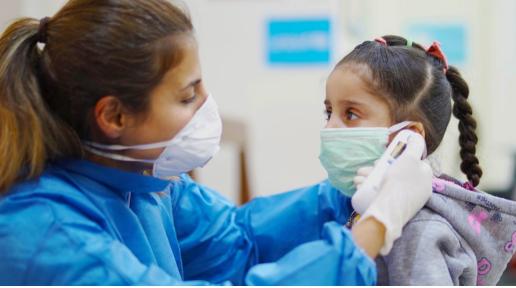 A nurse takes a girl’s temperature during COVID-19 outbreak