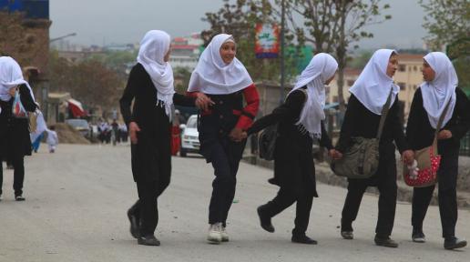 Beyaz başörtülü genç kızlar yolda yürüyor.
