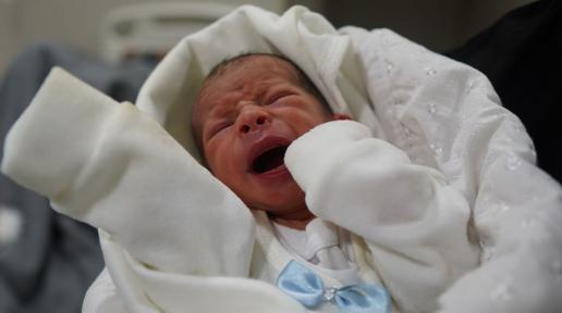 Beyaz battaniyeye sarılı yeni doğmuş bebek ağlıyor