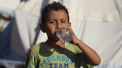 A five-year-old boy drinks bottled water delivered by UNICEF in the Khan Younis camp.