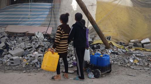 Gazzeli çocuklar su arayışında harabeye dönmüş binaların arasından geçiyor. 