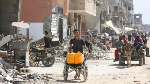 One man pushing a hand made looking cart, behind him a horse carriage on a destroyed street in Gaza